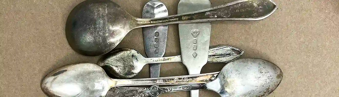 Close-up of vintage silver spoons showing mixed hallmarks including Sterling, 925, and EPNS on the handles.