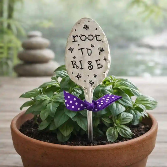 Decorative garden spoon with 'Root to Rise' text in a pot of plants.
