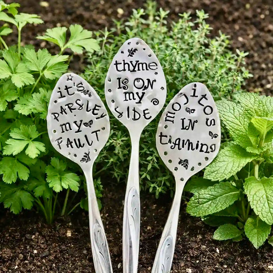 Three silver plate teaspoons with humorous garden, placed among plants.