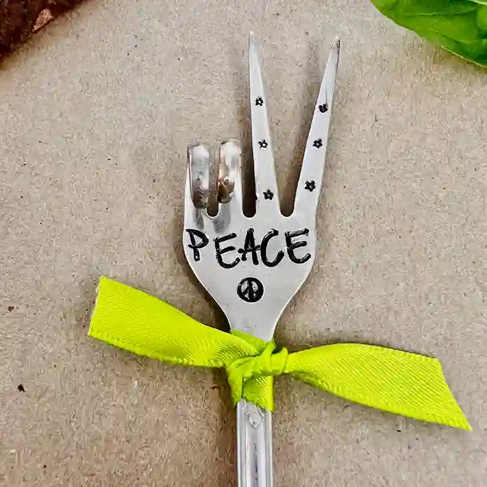 PEACE fork (two-finger peace sign) with yellow ribbon made from vintage silver-plate flatware on tan background