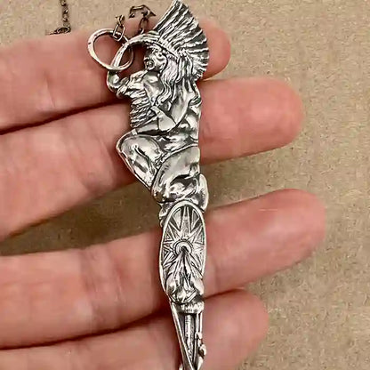 Silver-plate pendant of a stylized Native American figure made from a vintage souvenir spoon handle in hand