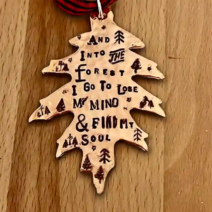 And Into The Forest I Go To Lose MY Mind & Find My Soul stamped into leaf-shaped copper ornament on wood background