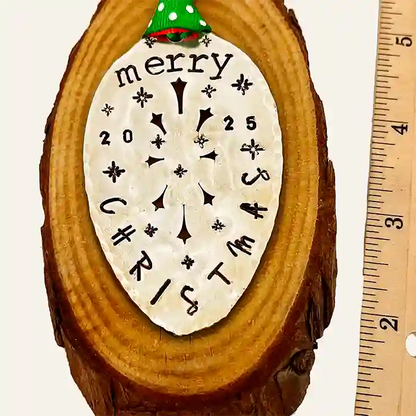 Vintage silver-plate slotted serving spoon with 2025 Christmas stamped on it, laying on piece of wood, measures 3 inches