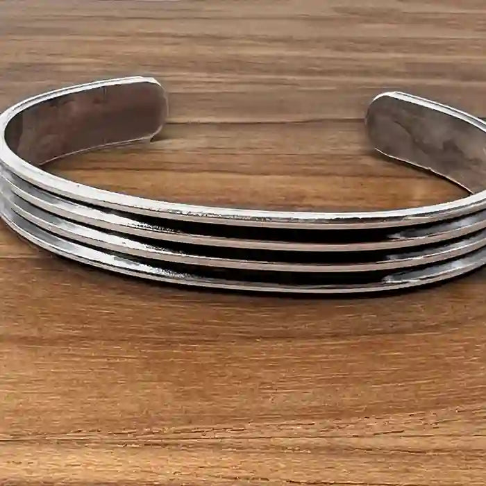 Sterling Silver bangle bracelet with three bands on wood table  background