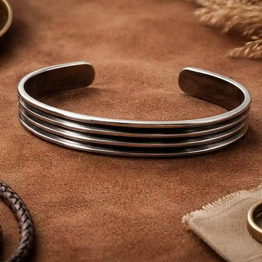 Silver bracelet on a brown textured surface with natural elements.