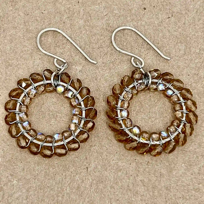 Pair of hoop earrings with brown beads on a beige background