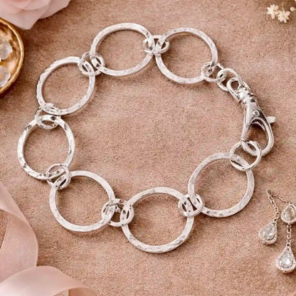 Silver chain bracelet on a textured surface with a soft focus background